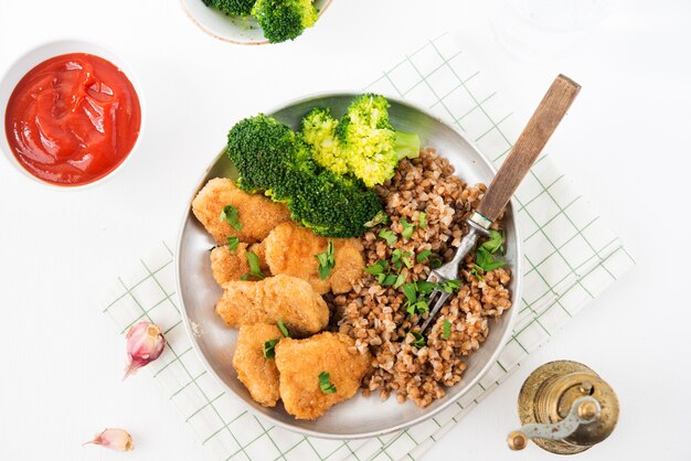 Hausgemachte Hühnernuggets mit Buchweizen und Gemüse auf einem Teller