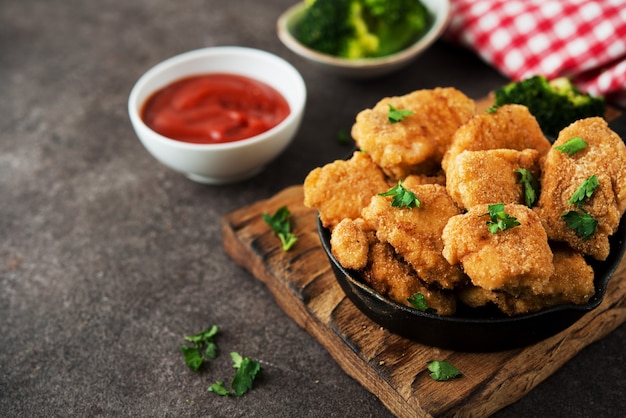 Hausgemachte Hühnernuggets mit Gemüse auf einem Holzbrett