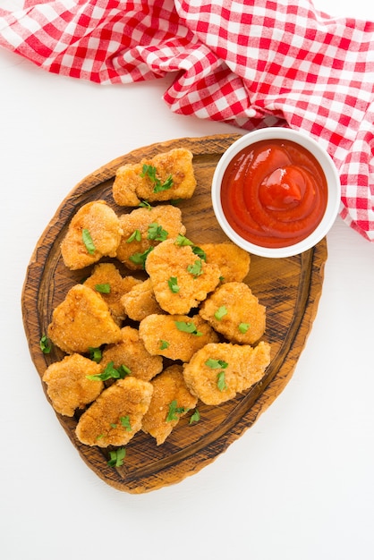 Hausgemachte Hühnernuggets mit Ketchup auf einem Holzbrett