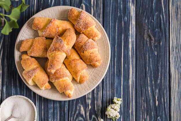 Hausgemachte Hüttenkäse-Minicroissants auf einem blauen hölzernen Hintergrund. Frühstück mit Croissants