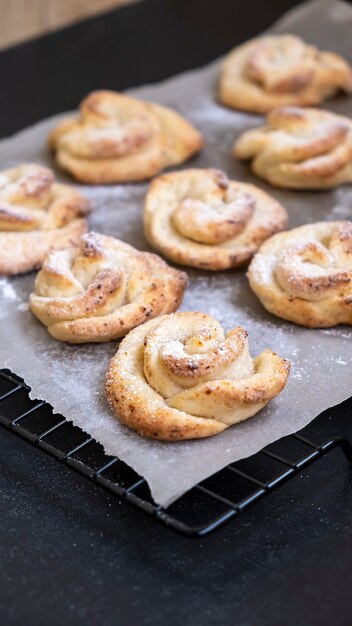 Hausgemachte Hüttenkäse-Shortbread-Plätzchen formen Rose auf Kühlregal. Dunkler Hintergrund.