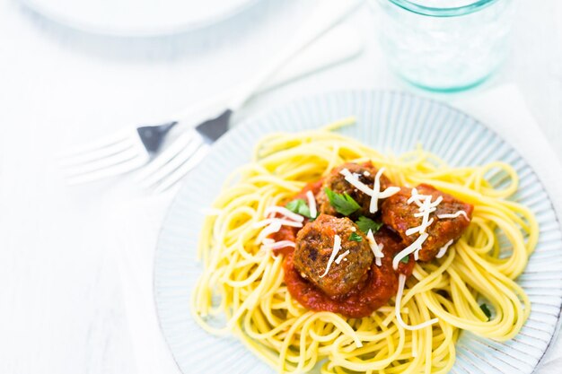 Hausgemachte italienische Fleischbällchen garniert mit Koriander und Parmesan über Spaghetti zum Abendessen.