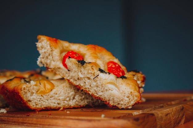 Hausgemachte italienische Focaccia mit Tomaten und Olivenöl auf rustikalem Holzhintergrund.