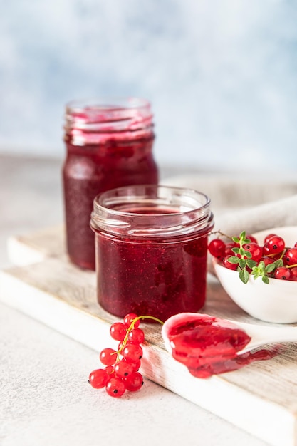 Hausgemachte Johannisbeermarmelade oder Gelee in Gläsern und rote Johannisbeeren frische Beeren