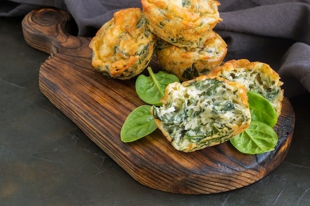 Hausgemachte Käsemuffins mit Spinat. auf dunklem Hintergrund.