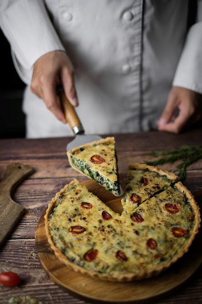 Hausgemachte käsige Spinat-Quiche zum Brunch. auf hölzernen Cafe Tisch gesetzt.