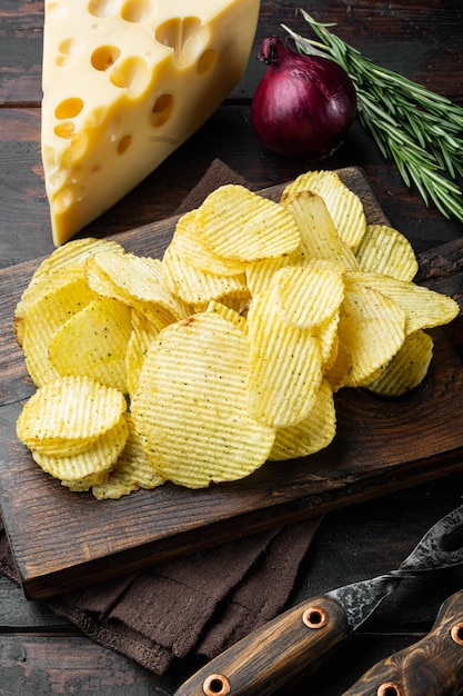 Hausgemachte Kartoffelchips mit Käse und Zwiebeln auf einem alten dunklen Holztisch