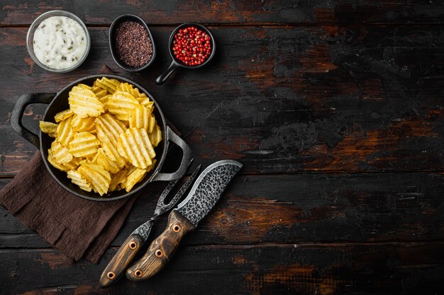 Hausgemachte Kartoffelchips mit saurer Sahne auf einem alten dunklen Holztisch