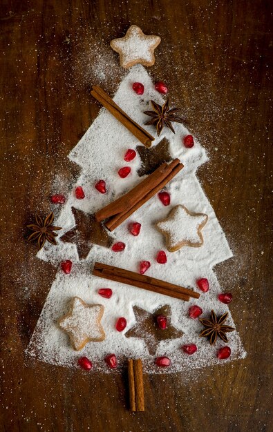 Hausgemachte Kekse gefaltet in Form eines Weihnachtsbaumes mit Zimt auf einem Backblech mit Puderzucker, Draufsicht