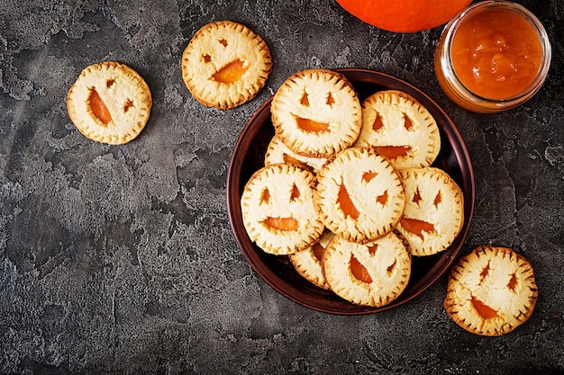 Hausgemachte Kekse in Form von Halloween-Kürbissen auf dem dunklen Tisch Top-View