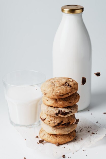 Hausgemachte Kekse werden mit Schokolade auf dem Hintergrund einer Milchflasche und eines Glases bestreut