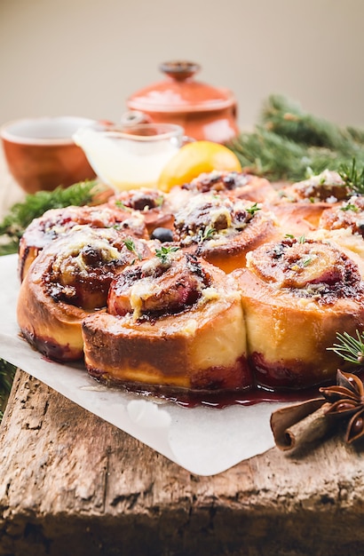 Hausgemachte köstliche Zimtschnecken mit Zitrone und Beeren über hölzernem Hintergrund