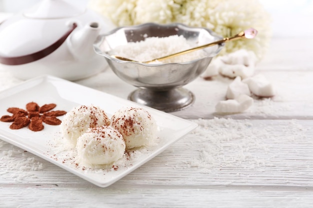 Hausgemachte Kokosbonbons auf Teller, auf hellem Hintergrund