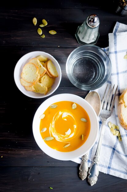 Hausgemachte Kürbissuppe in weißer Keramikschale mit Samen, saurer Sahne