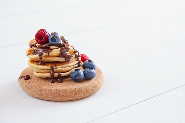 Hausgemachte leckere Pfannkuchen mit frischen Beeren und flüssiger Schokolade Gesundes Frühstück von Pfannkuchen mit Himbeeren und Blaubeeren Hintergrund