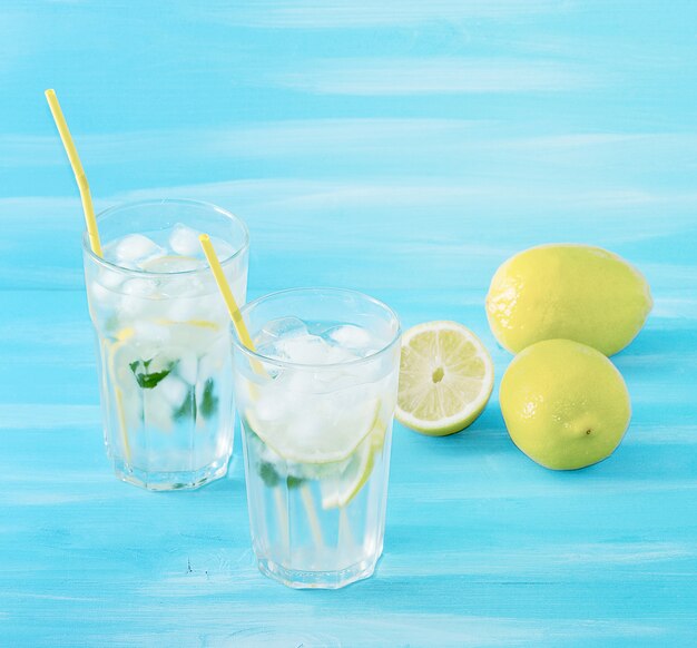 Hausgemachte Limonade mit Strohhalmen zum Trinken von Zitrone, Minze, Eis und Wasser in Gläsern