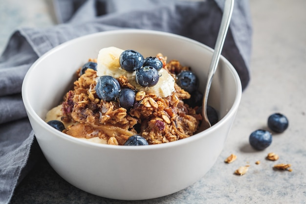 Hausgemachte Müslischale mit Blaubeeren, Banane und Honig.