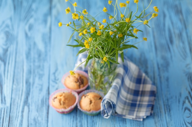 Hausgemachte Muffins in der blauen Serviette auf blauem Holztisch