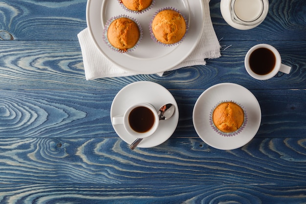 Hausgemachte Muffins mit Schokoladenstückchen und Blaubeeren mit einem Glas Milch und Kaffee. Cupcake mit Schokolade.