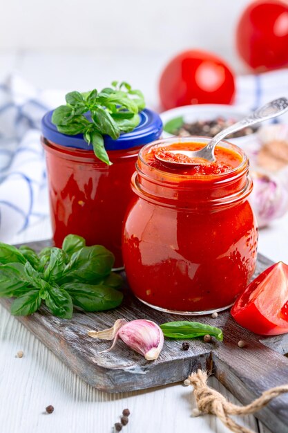 Hausgemachte neapolitanische Tomatensauce mit Knoblauchpfeffer und frischem Basilikum in Glasgläsern mit selektivem Fokus