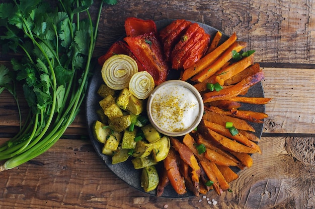 Hausgemachte ofengebackene Süßkartoffeln mit Tomaten, Zwiebeln, Paprika und Soße auf Draufsicht des gesunden Essenskonzepts im rustikalen Hintergrund