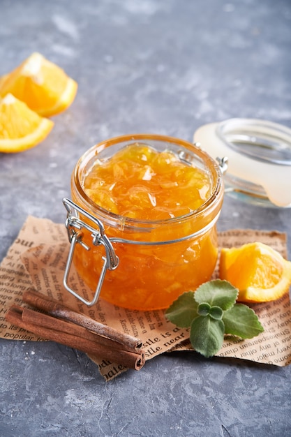 Hausgemachte Orangenmarmelade im Glas auf einem grauen Tisch. Lebensmittelhintergrund