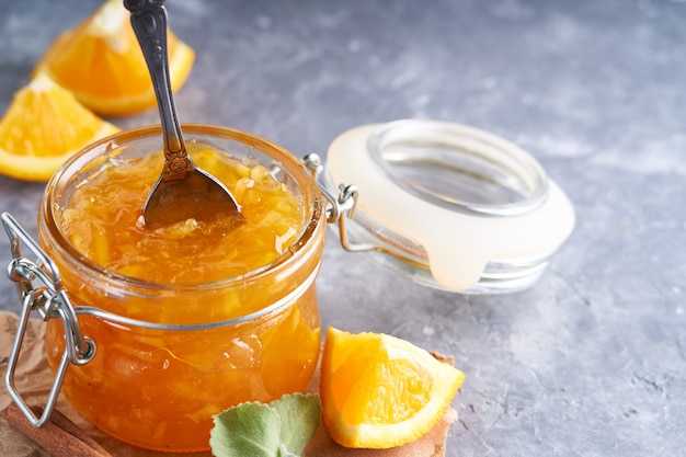 Hausgemachte Orangenmarmelade im Glas auf einem grauen Tisch. Lebensmittelhintergrund