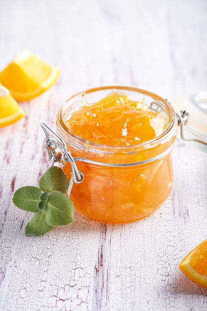 Hausgemachte Orangenmarmelade im Glas auf einem weißen Tisch. Lebensmittelhintergrund