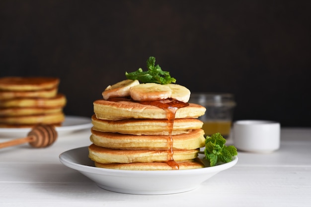 Hausgemachte Pfannkuchen mit Banane und Sirup zum Frühstück auf dem Küchentisch.