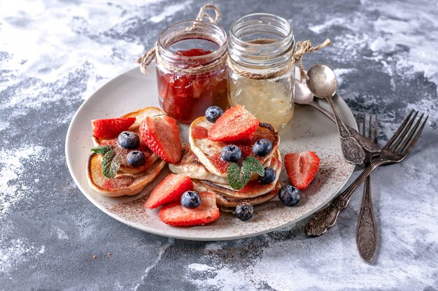 Hausgemachte Pfannkuchen mit Erdbeermarmelade, frische Erdbeeren und Blaubeeren