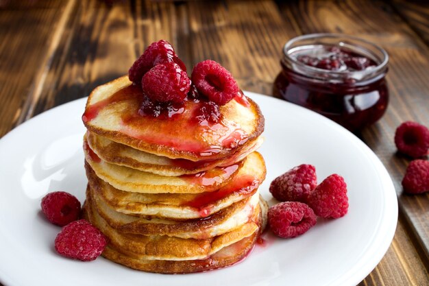 Hausgemachte Pfannkuchen mit Himbeermarmelade in der weißen Platte auf dem Holz