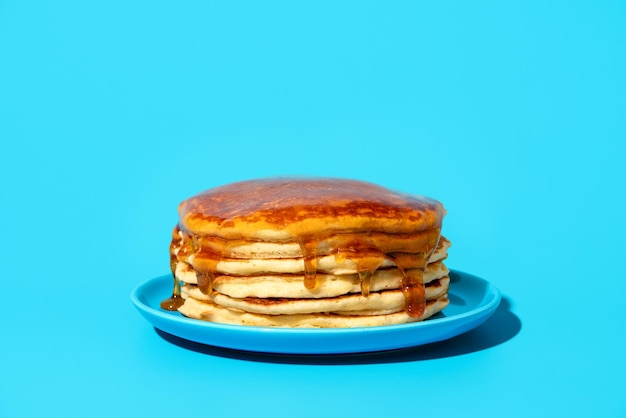 Hausgemachte Pfannkuchen mit Sirup isoliert auf blauem Hintergrund