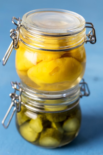 Hausgemachte Pickles Konserven Gurken und kleine gelbe Squash auf blauem Hintergrund vertikal