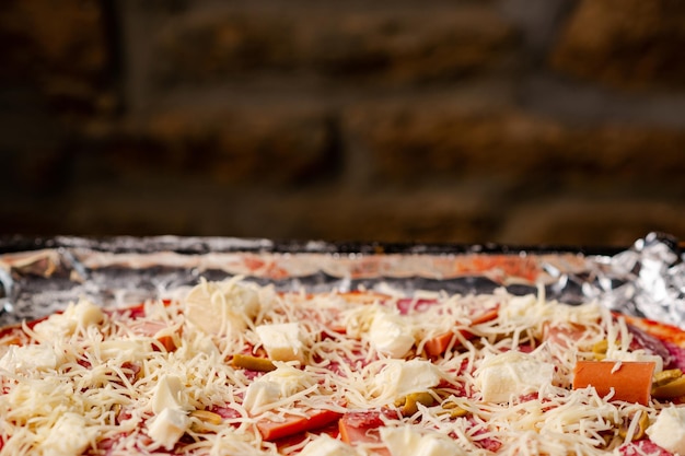 Hausgemachte Pizza auf Backblech kochen Rohe Pizza auf dem Hintergrund der Backsteinmauer