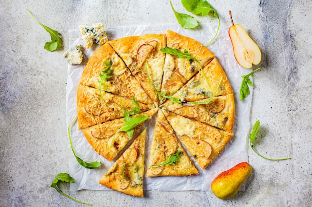 Hausgemachte Pizza mit Birne, Rucola und Käse, grauer Hintergrund