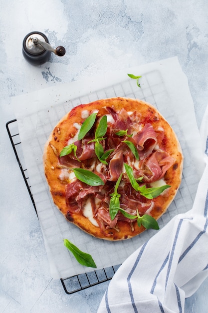 Hausgemachte Pizza mit Jamon, Mozzarella und frischen Basilikumblättern