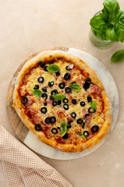Hausgemachte Pizza mit Schinken, schwarzen Oliven, Käse und frischem Basilikum Draufsicht