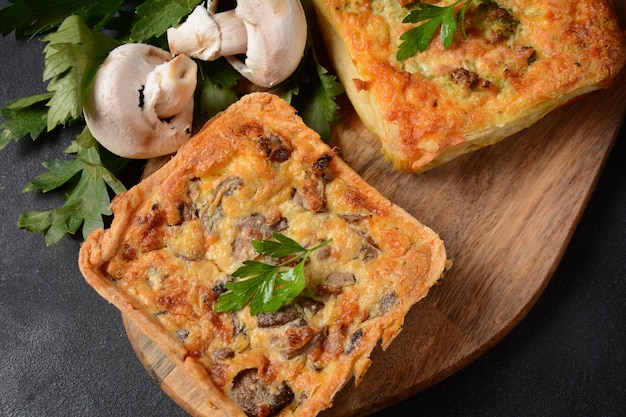 Hausgemachte Quiche oder Torte mit Brokkoli, Gewürzen, Champignons und Käse auf grauem Hintergrund.