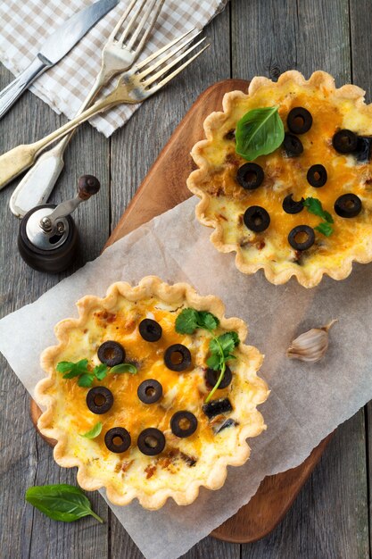 Hausgemachte Quiche-Torte mit Huhn, Aubergine, Oliven und Käse auf alter Holzoberfläche. Draufsicht. Selektiver Fokus.