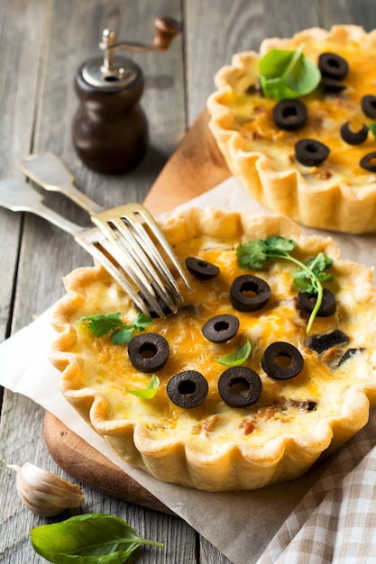 Hausgemachte Quiche-Torte mit Huhn, Auberginen, Oliven und Käse auf alter Holzoberfläche. Selektiver Fokus.