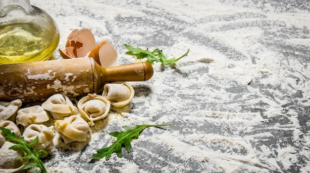 Hausgemachte Ravioli mit Olivenöl und Nudelholz. Auf dem Steintisch mit Mehl. Freier Platz für Text.