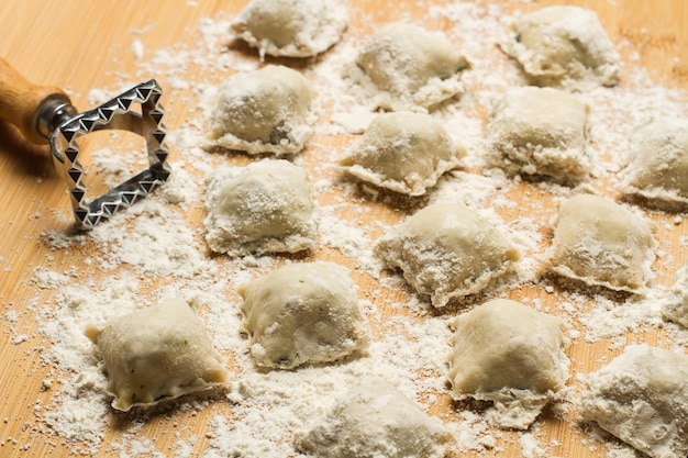 Hausgemachte Ravioli und Ravioliform auf einem Holztisch