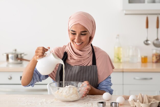 Hausgemachte Rezepte Glückliche muslimische Dame in Hijab und Schürze Backen in der Küche