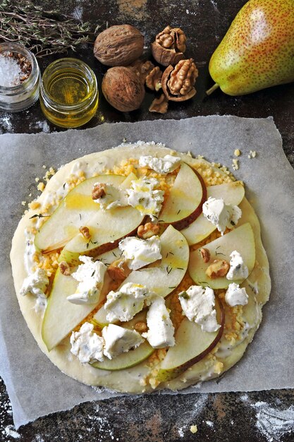 Hausgemachte rohe Pizza mit Birne, Käse und Walnüssen.