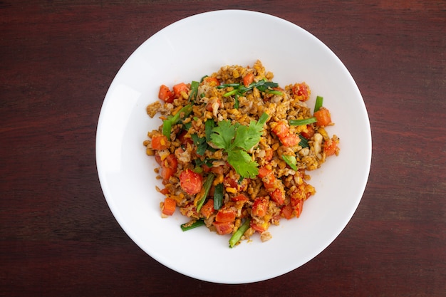 Hausgemachte Rühreier mit Karotten und Tomaten in weißer Platte auf Holztisch