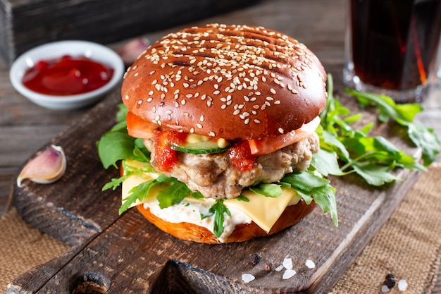 Hausgemachte saftige Burger mit Rindfleisch, Käse und Rucola auf einem Holztisch. Amerikanische Küche. Fastfood