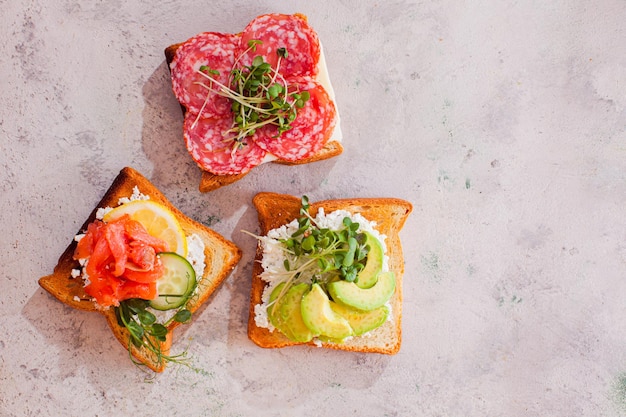 Hausgemachte Sandwiches auf heller Murble-Oberfläche Closeup Lachssalami und Avocado-Toast-Sandviches Lieblingssnacks für einen harten Arbeitstag