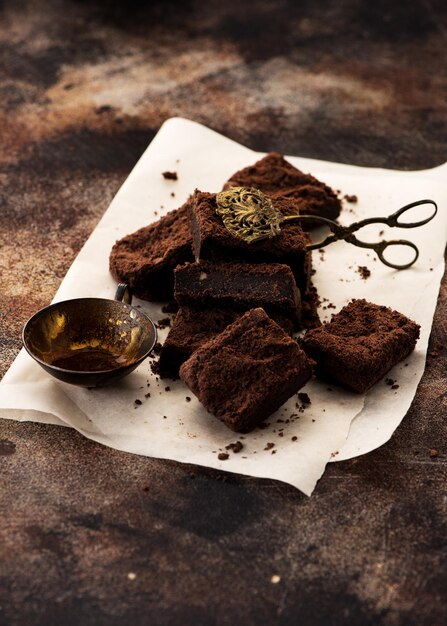 Hausgemachte Schokoladenbrownies und leere Tasse Kaffee auf braunem Betonhintergrund