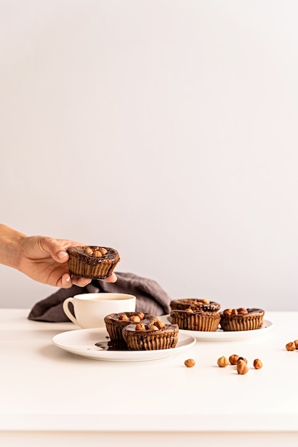 Hausgemachte Schokoladencupcakes mit Glasur und Walnüssen und einer Tasse Kaffee auf weißem Tisch