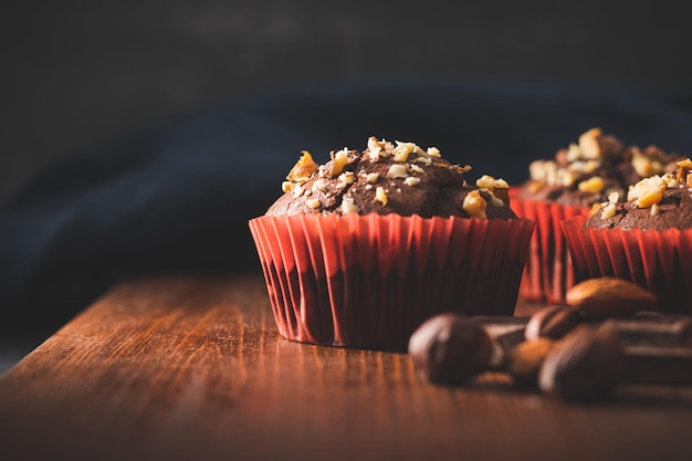 Hausgemachte Schokoladenmuffins oder Cupcakes mit Nüssen auf einem Holzbrett